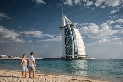 Vue extérieure du Burj Al Arab depuis la plage de Dubaï avec des touristes en premier plan et le golfe Arabique en arrière-plan