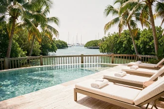 Piscine avec vue sur le lagon turquoise du Coral Lagoon Resort à Marathon en Floride, entourée de palmiers tropicaux et de transats blancs sur une terrasse en travertin