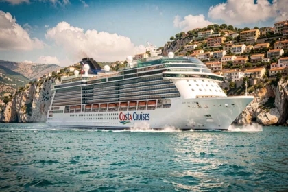Bateau de croisière Costa naviguant en Méditerranée près d'une côte rocheuse avec villages pittoresques