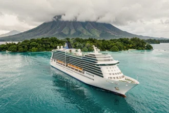 Le navire de croisière Paul Gauguin naviguant au large d'une île tropicale luxuriante en Polynésie française