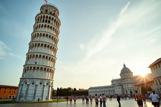 Vue grand angle de la tour penchée de Pise avec des touristes lisant les nouvelles règles d'accès en 2026
